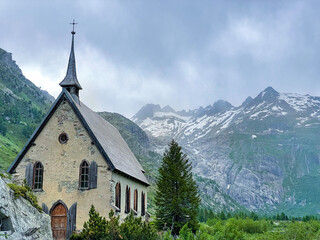 Fototapeta na wymiar COPY SPACE: Stunning glaciers tower above a historic church in the Swiss Alps.