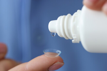 Woman drips liquid into contact lens for eyes closeup