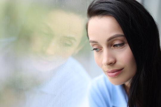 Pensive pensive girl sits alone and looks out window closeup