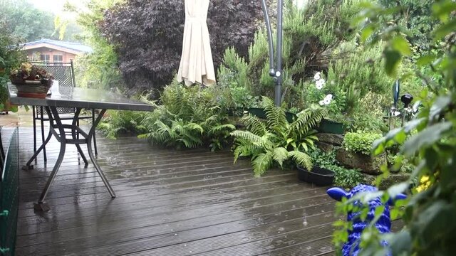 heftiger Sommer-Regennschauer prasselt auf eine Holzterrasse