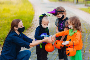 Three kid with a basket for sweets gets candies wearing face mask protecting from COVID 19