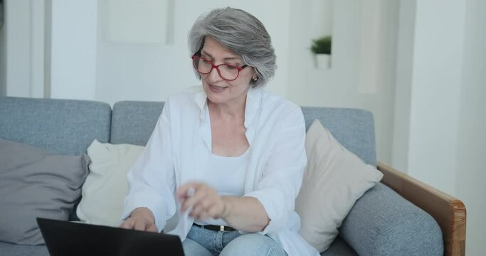 Positive Grandma Blogger Answers Questions From Subscribers And Comments On Social Media. Senior Woman Writes Posts, Notes And Useful Tips Using Laptop. Happy Socialized Old Age With Modern Technology