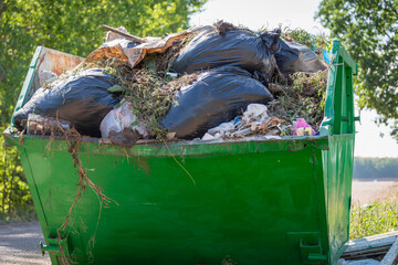 Metal container with rubbish. There are garbage bags in the container.