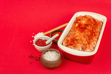 Pickled pork loin ready to bake on a red matte background