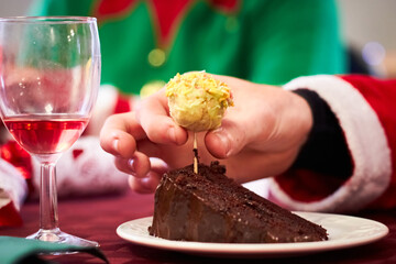 Slice of chocolate fudge cake garnished with cake pop being eaten with a spoon on a red tablecloth for christmas