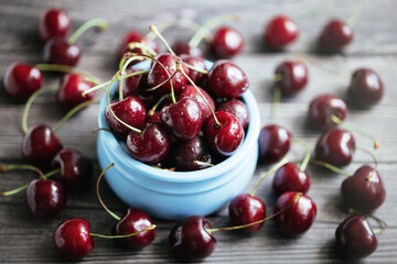 Fresh juicy cherries in a blue bowl on a gray wooden background. Cherry closeup in a bowl. Berries in drops of water. Food background.
