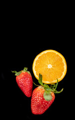 
Orange and strawberries cut in half, on black background