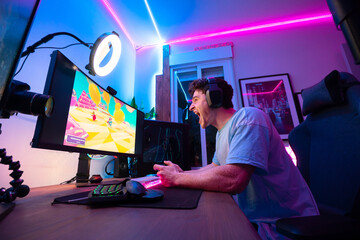 young white caucasian boy in front of the screen playing video games with blue and pink led lights...