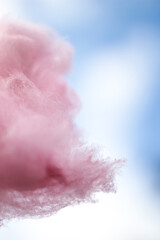 Pink cotton candy on a stick held against the sky to look like a cloud.