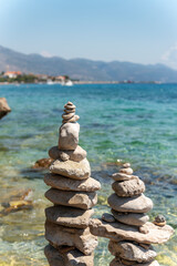 Pyramid stones balance on the beach on background of blue sea and sky