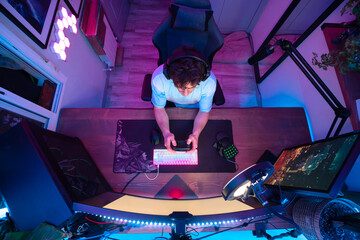 young white caucasian boy in front of the screen playing video games with blue and pink led lights set recording voice streaming live