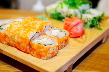 Sushi with salmon, cucumber and cheese on a wooden board