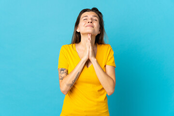 Young slovak woman isolated on blue background keeps palm together. Person asks for something