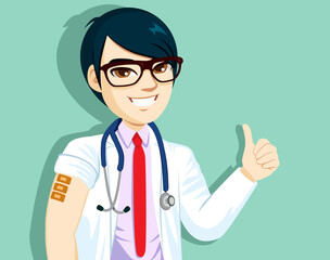 Positive Asian male doctor with glasses shows vaccinated arm with three adhesive bandages gets third dose of vaccine happy to feel protected thumb up hand gesture