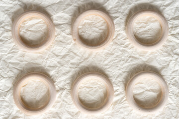plain, untreated wooden crafting rings arranged on crumpled ivory paper - photographed under ambient light