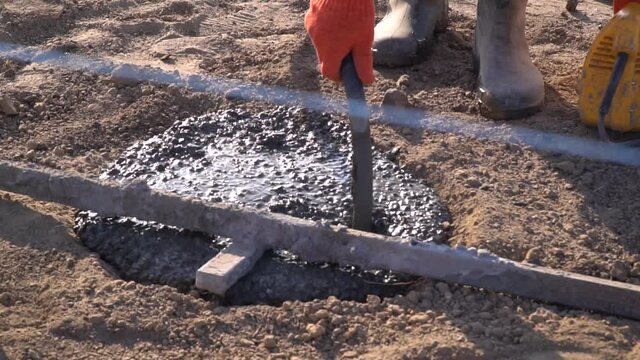 Worker is measuring the depth of fresh concrete poured into a hole
