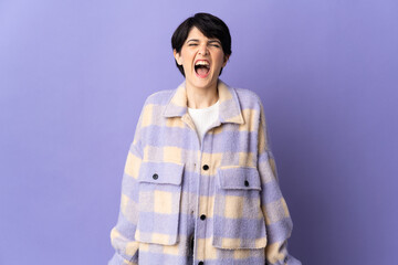Woman with short hair isolated on purple background shouting to the front with mouth wide open