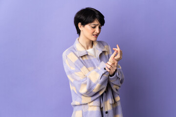 Woman with short hair isolated on purple background suffering from pain in hands