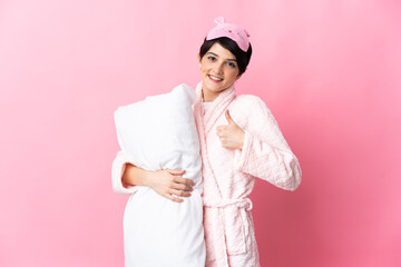 Woman with short hair isolated on pink background in pajamas and with thumbs up because something good has happened
