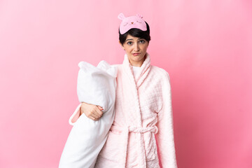 Woman with short hair isolated on pink background in pajamas and with sad expression