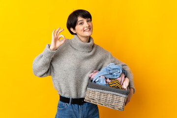 Woman with short hair holding a clothes basket showing ok sign with fingers