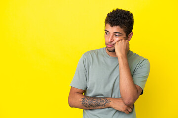 Young handsome Brazilian man isolated on yellow background with tired and bored expression