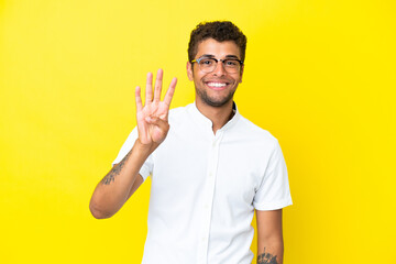 Young handsome Brazilian man isolated on yellow background happy and counting four with fingers