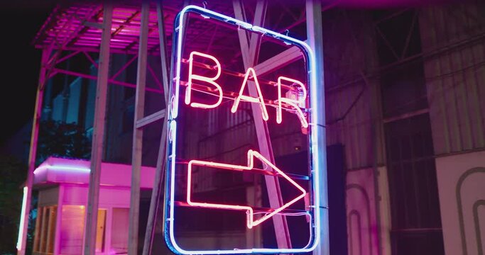 4K Neon bar sign medium shot . Night exterior video footage of vintage neon sign. A nighttime exterior shot of a generic, unbranded bar and restaurant in street . Gimbal shot .