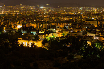 Fototapeta na wymiar ギリシャ　アテネのアレオパゴスの丘から見える夜景と古代アゴラ内にあるライトアップされたヘパイストス神殿