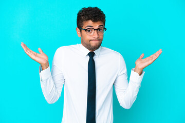 Young business Brazilian man isolated on blue background having doubts while raising hands