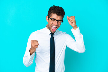 Young business Brazilian man isolated on blue background celebrating a victory