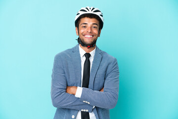 Young business Brazilian man with bike helmet isolated on blue background keeping the arms crossed...