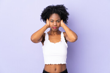 Young African American woman isolated on purple background frustrated and covering ears