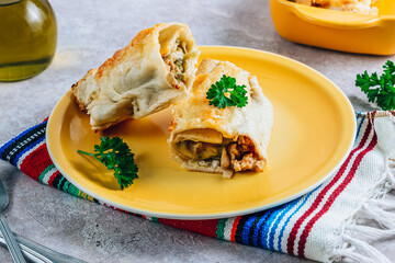 Mexican enchiladas with chicken and cheese. Served in yellow plate on stone background. Mexican cuisine. 