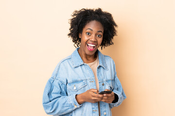 Young African American woman isolated on beige background surprised and sending a message