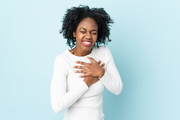 Young African American woman isolated on blue background having a pain in the heart