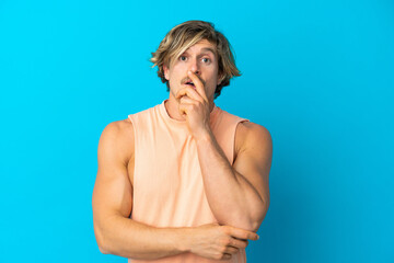 Handsome blonde man isolated on blue background surprised and shocked while looking right