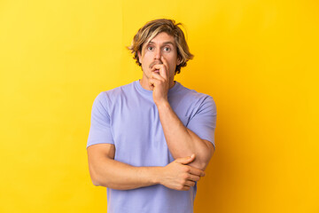 Handsome blonde man isolated on yellow background surprised and shocked while looking right