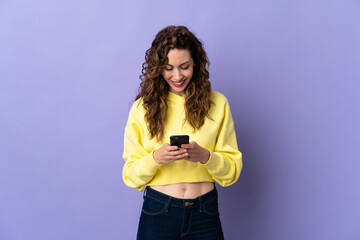 Young caucasian woman isolated on purple background sending a message with the mobile