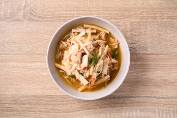 Local Thai food, Fermented bamboo shoot spicy soup with pork in a bowl on wooden background, Table top view