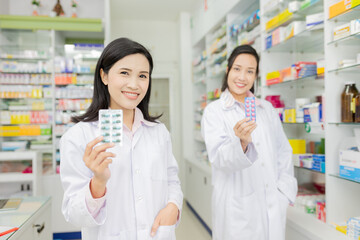two asian pharmacist standing in drugstore, they feeling happy and smile, teamwork and professional...