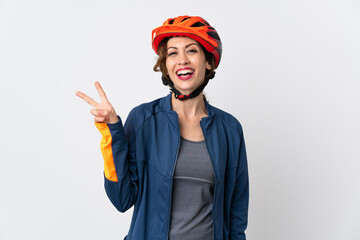 Young cyclist woman isolated on white background smiling and showing victory sign