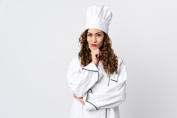 Young chef woman isolated on white background having doubts while looking up