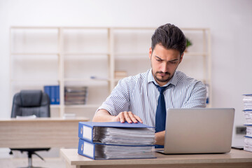 Naklejka premium Young male employee and too much work in the office