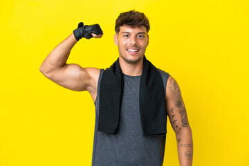 Young sport caucasian man with towel isolated on yellow background doing strong gesture