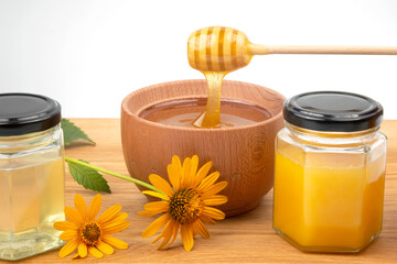 fresh floral honey dripping from a spoon into a wooden plate on a white background. organic vitamin health food