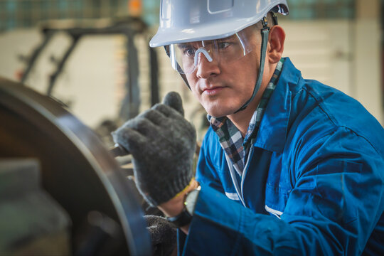 mechanic engineer operate lathe machine to make metal part in factory