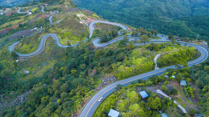 View of the long road up to the hill with green grass, forest, mountain and blue sky background, Phu Thap Boek, Phetchabun Province, Thailand