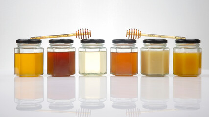 Hexagonal jars with different types and colors of fresh flower honey and a honey spoon. vitamin...