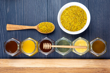 Hexagonal jars with different types and colors of fresh flower honey, spoon, pollen. vitamin food for health and life